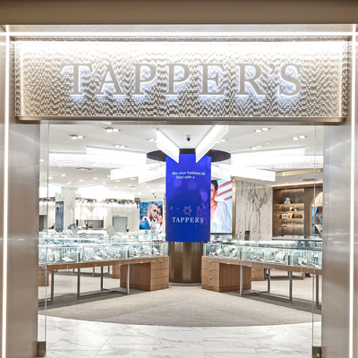 Luxury jewelry store Tappers Jewelry at Somerset Collection North in Troy, MI entrance with illuminated signage, display cases, decorated Christmas trees, and grand opening text on glass windows