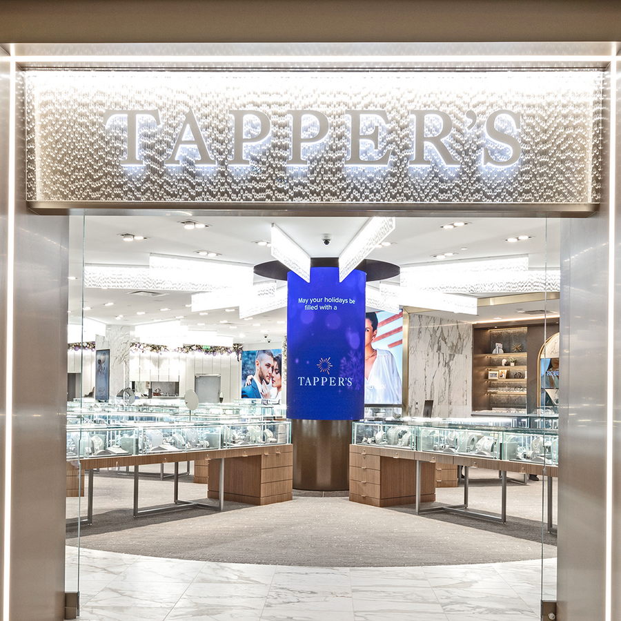 Luxury jewelry store Tappers Jewelry at Somerset Collection North in Troy, MI entrance with illuminated signage, display cases, decorated Christmas trees, and grand opening text on glass windows