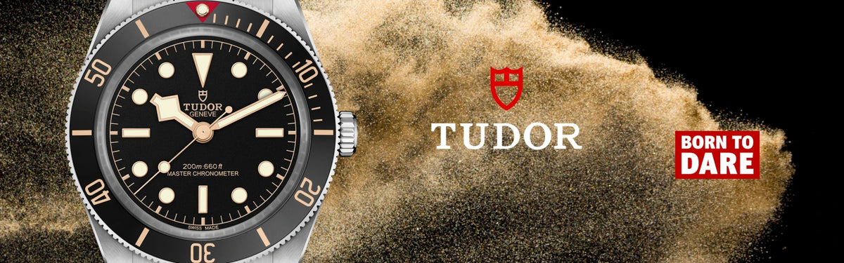 A close-up of a TUDOR Black Bay 58 watch with a black dial and rotating bezel on the left, set against a dramatic background of gold dust being blown back by wind. The right side features the Tudor crest logo, the word 'TUDOR' in white, and a red badge that reads 'BORN TO DARE'.
