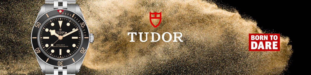 A close-up of a TUDOR Black Bay 58 watch with a black dial and rotating bezel on the left, set against a dramatic background of gold dust being blown back by wind. The right side features the Tudor crest logo, the word 'TUDOR' in white, and a red badge that reads 'BORN TO DARE'.