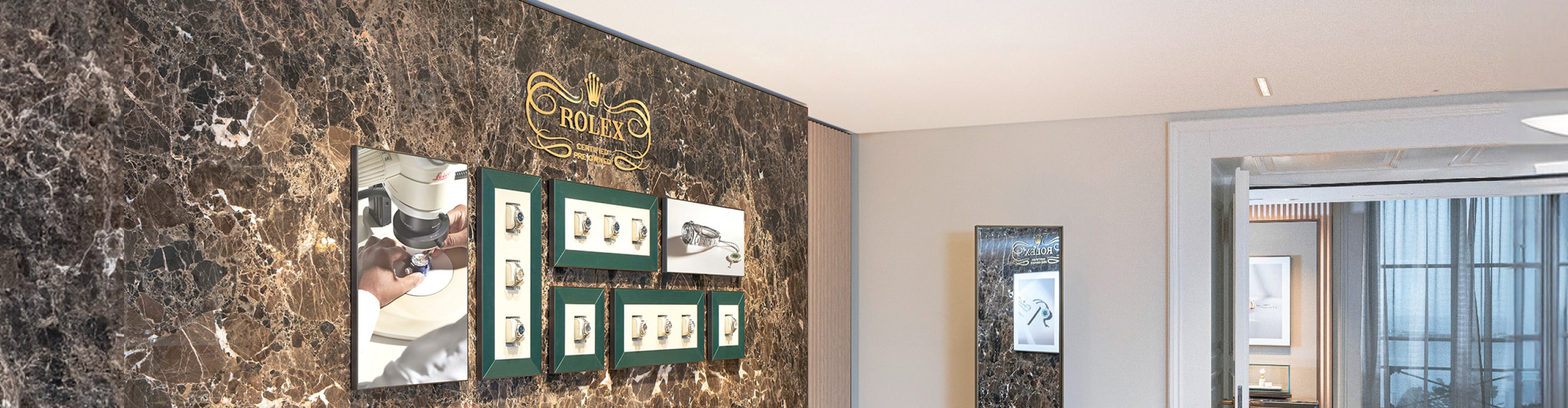 Rolex pre-owned showroom interior with marble wall featuring watchmaking process photographs in green frames