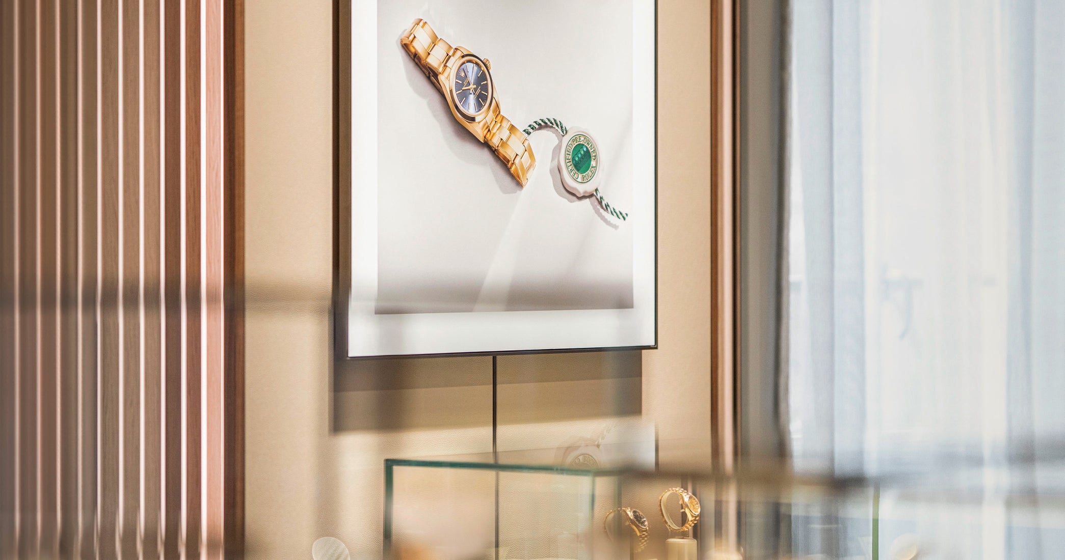 Gold-tone wristwatch and Rolex hang tag displayed in minimalist gallery setting