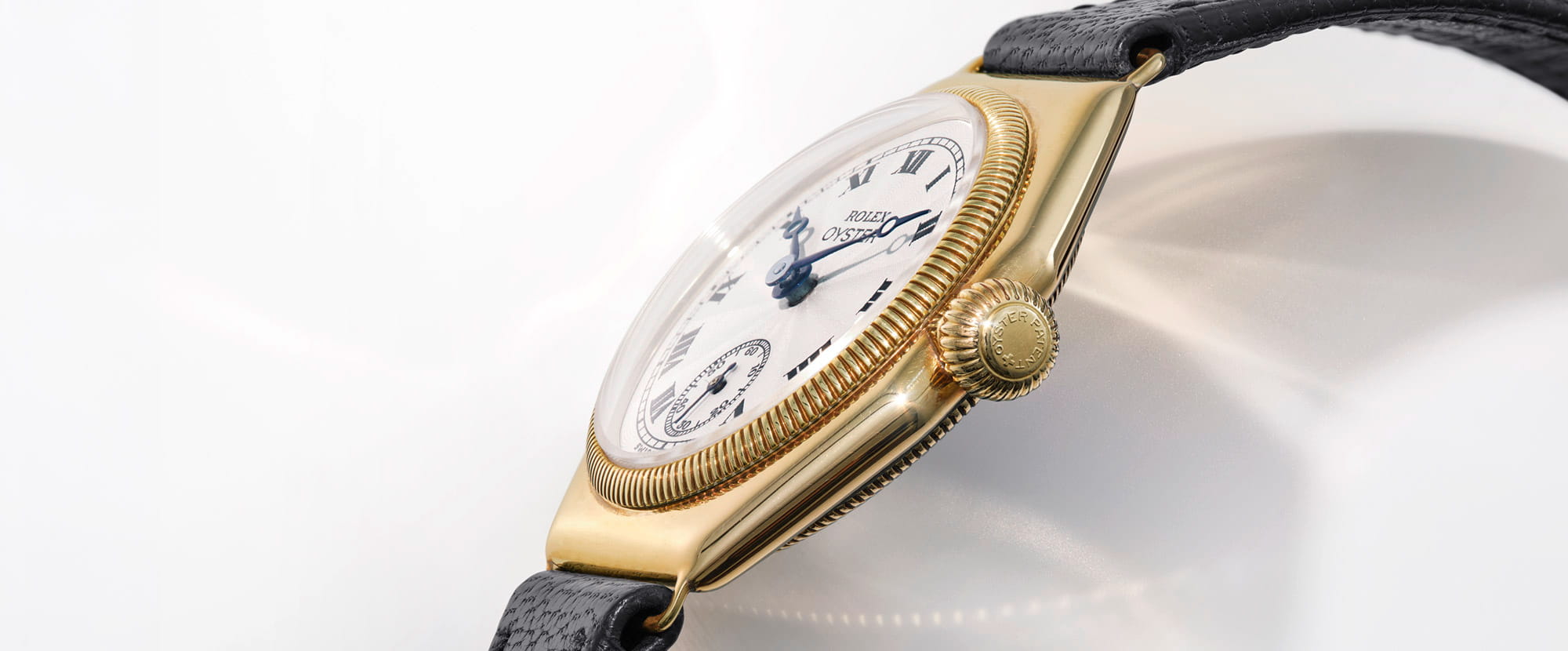Gold wristwatch with a white face on a light gray background