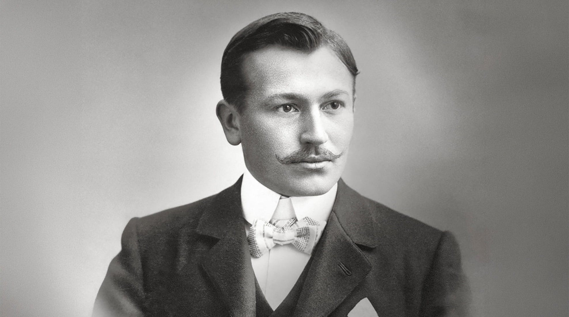 Black and white portrait of a man in formal attire with a bow tie against a plain background