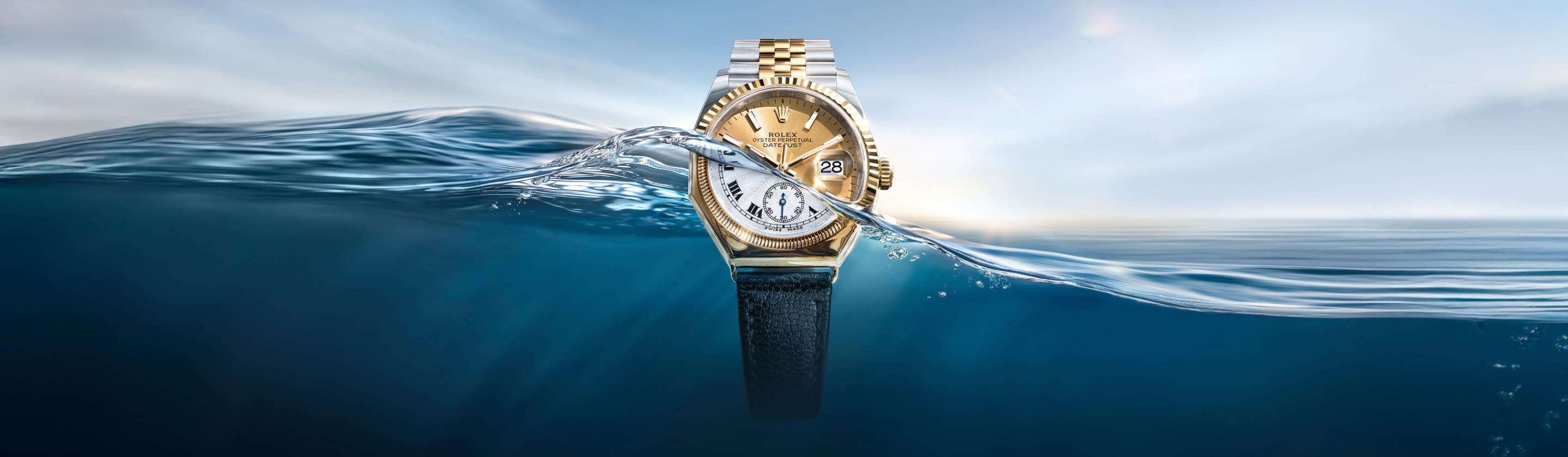 Gold watch with a black strap partially submerged in water, with a clear sky above.